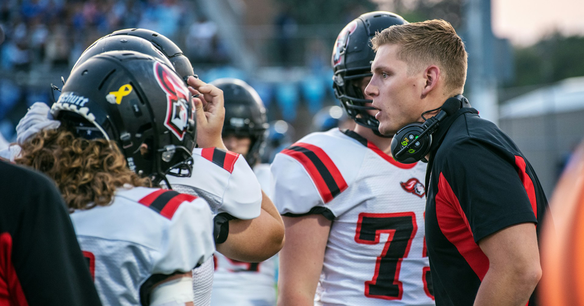 young football coach talking to players on the sideline during a game