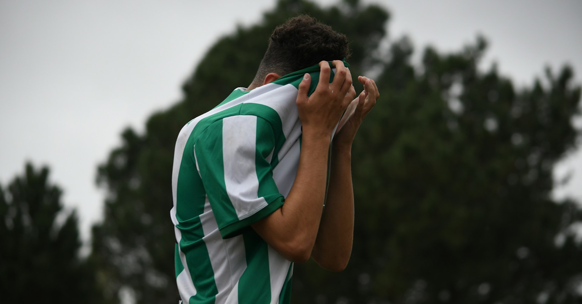 male soccer player hides face in jersey